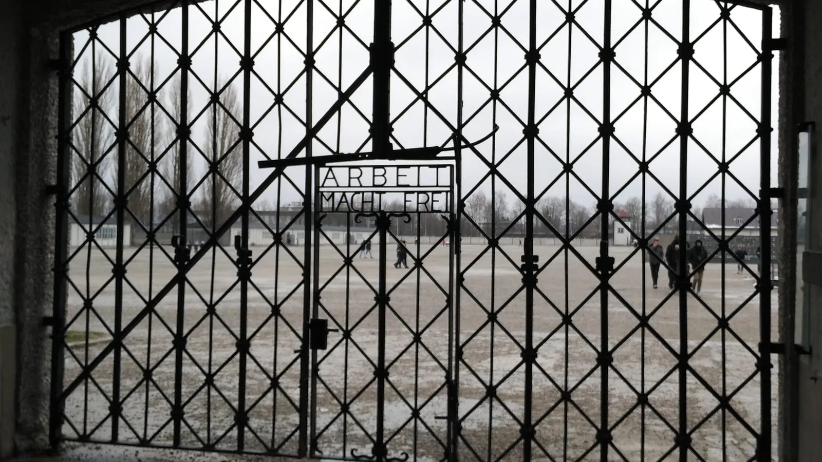 Puerta del antiguo campo de concentración de Dachau con el lema «Arbeit macht frei» y la plaza de recuento al fondo