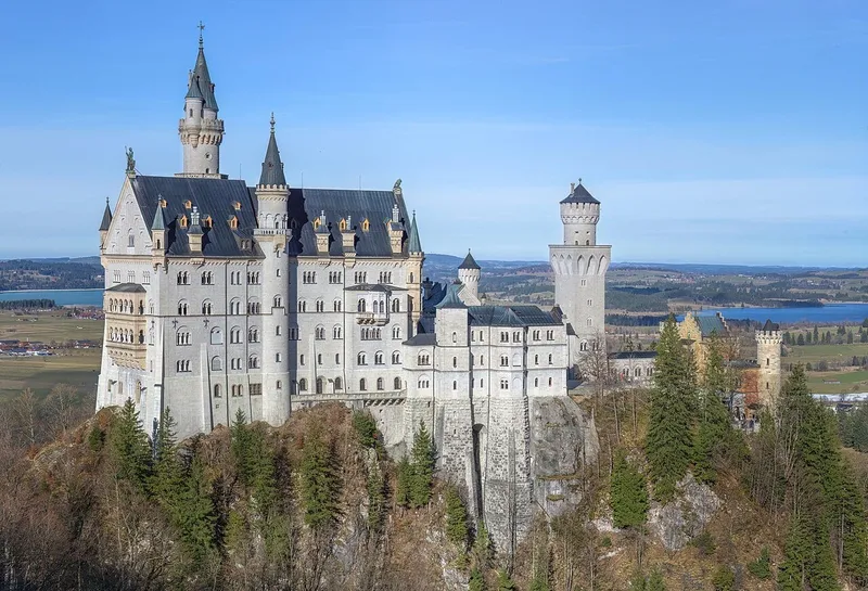 El castillo de Neuschwanstein sobre el bosque, con los lagos al fondo