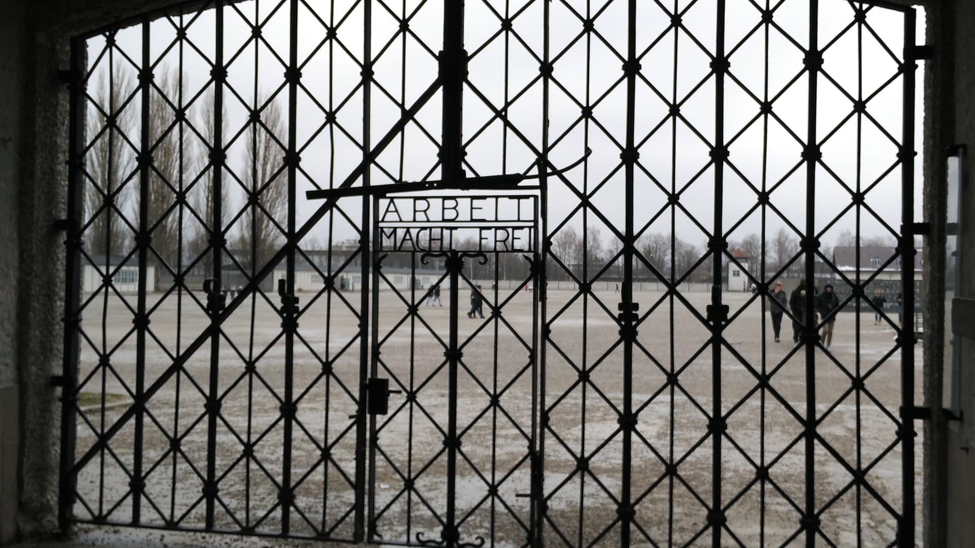 Puerta del antiguo campo de concentración de Dachau con el lema «Arbeit macht frei» y la plaza de recuento al fondo